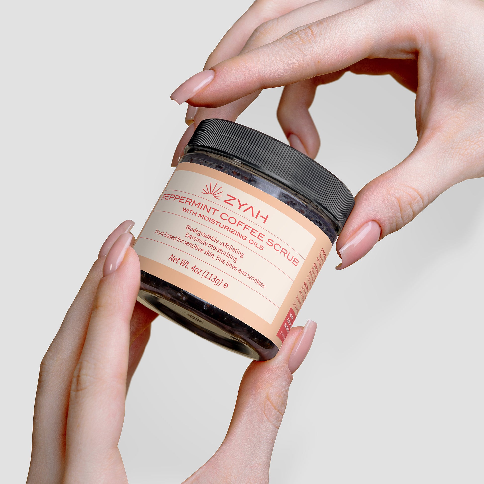 Jar of ZYAH peppermint coffee scrub Botanical Skincare  held by hands against a neutral background