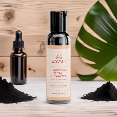 Zyah charcoal facial cleanser bottle with black powder and dropper bottle on a wooden surface.
